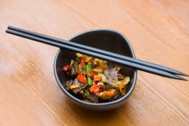 Prato chinês, carne com pimenta na tigela e pauzinhos nele — Fotografia de Stock
