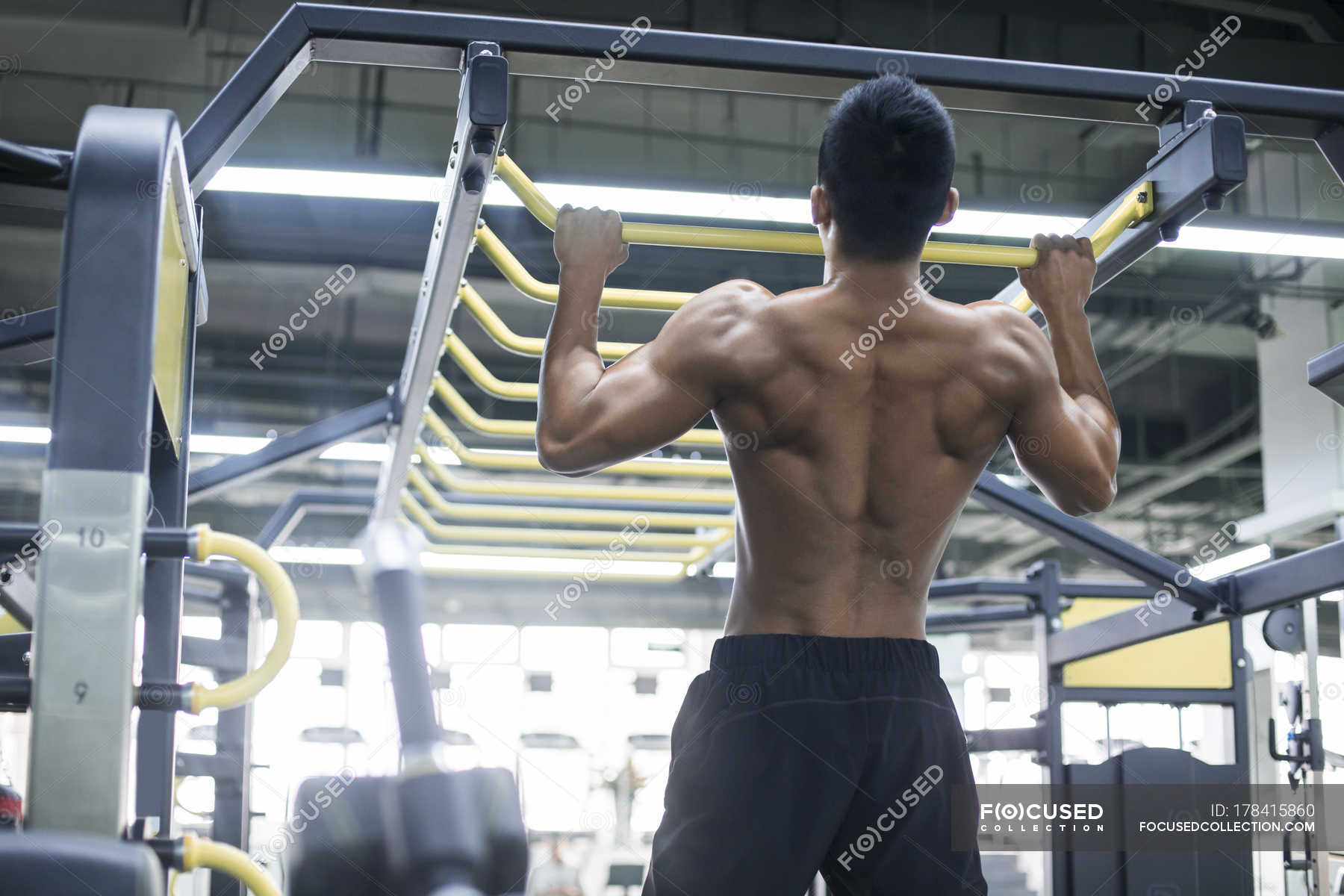 Young man pulling up at gym — male, selective focus Stock Photo