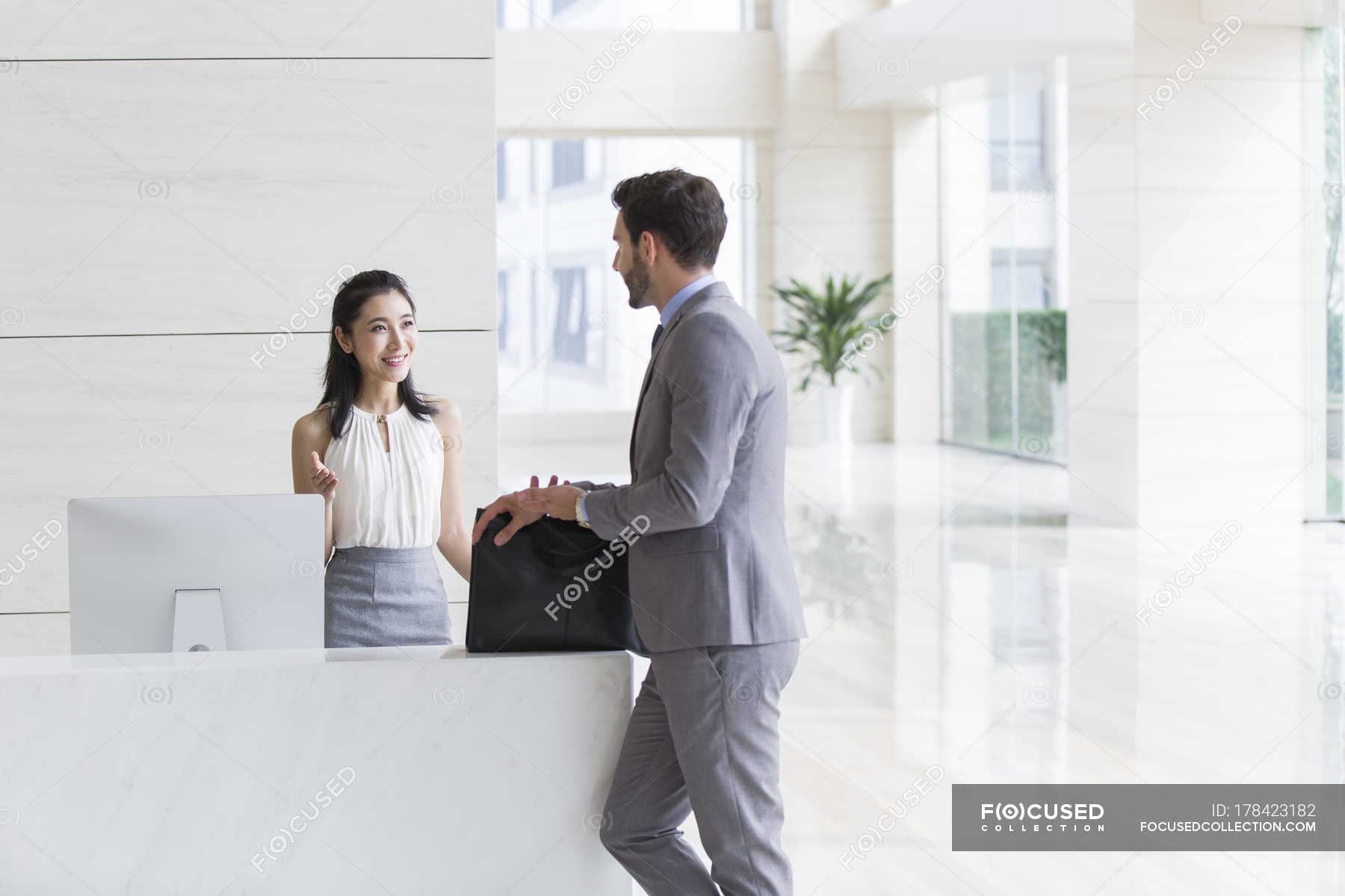 Businessman talking with receptionist in office building — woman ...