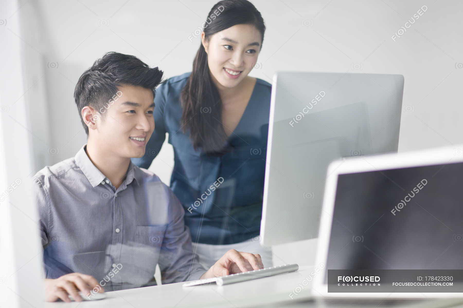 Chinese co-workers using computer in office — selective focus ...