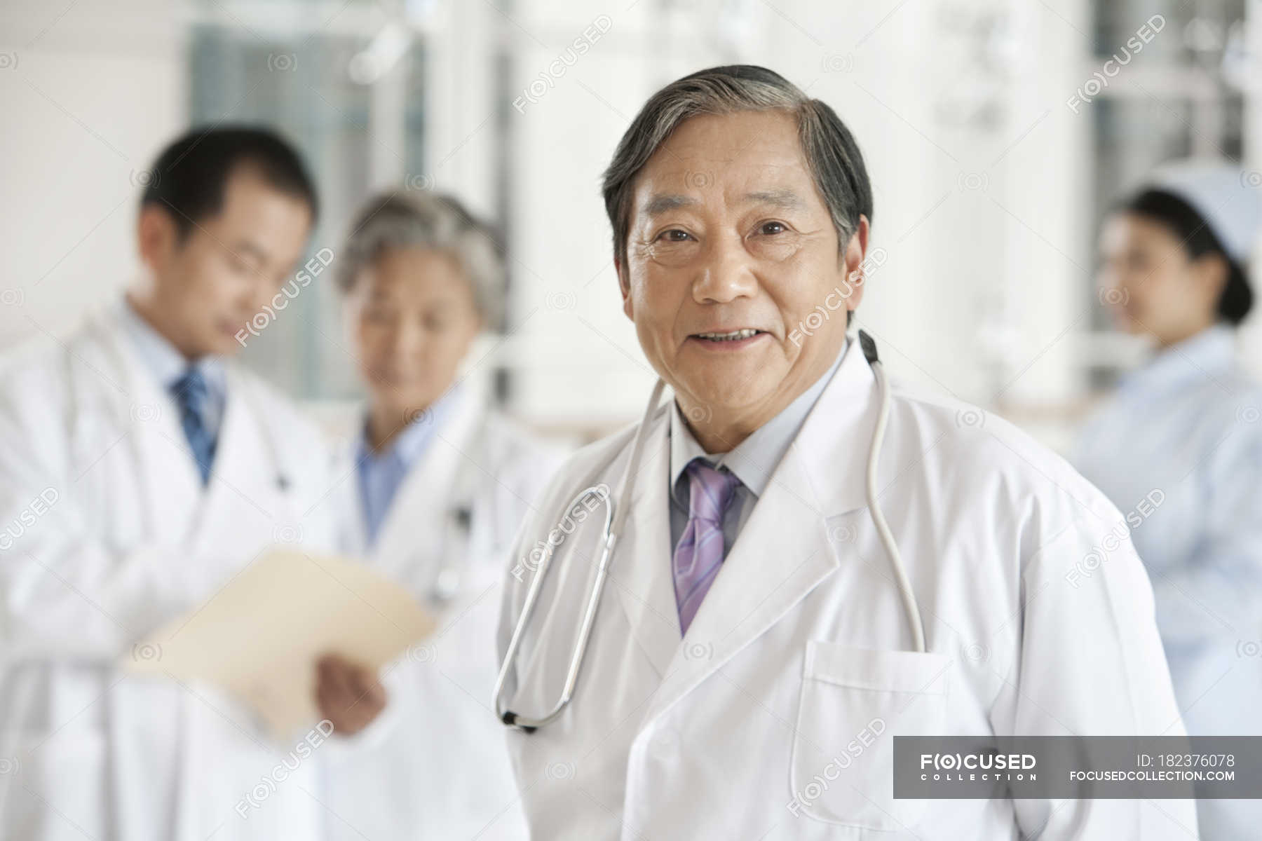 Chinese doctor standing in hospital with colleagues in background