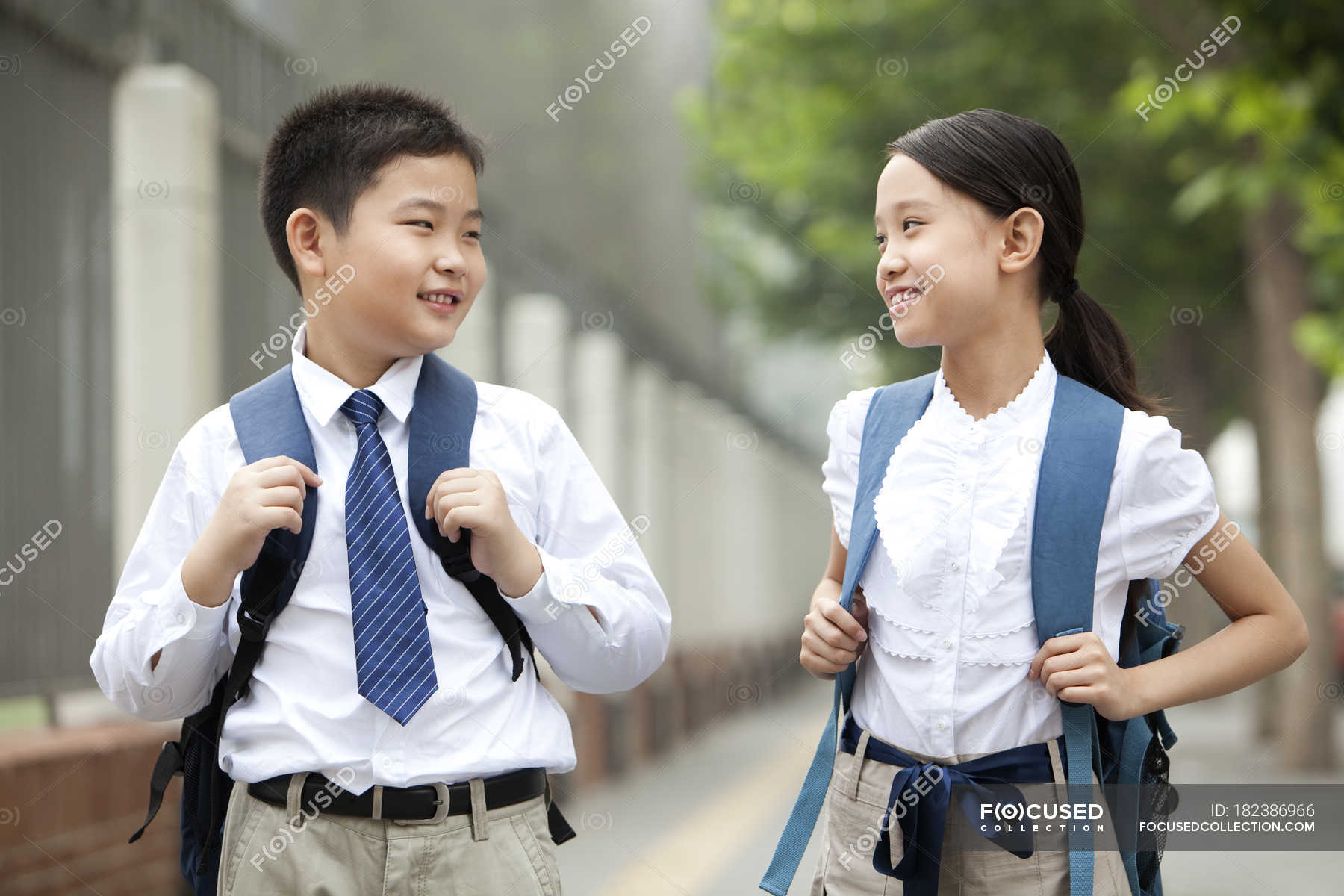 Cheerful classmates in school uniform posing on street — childhood ...