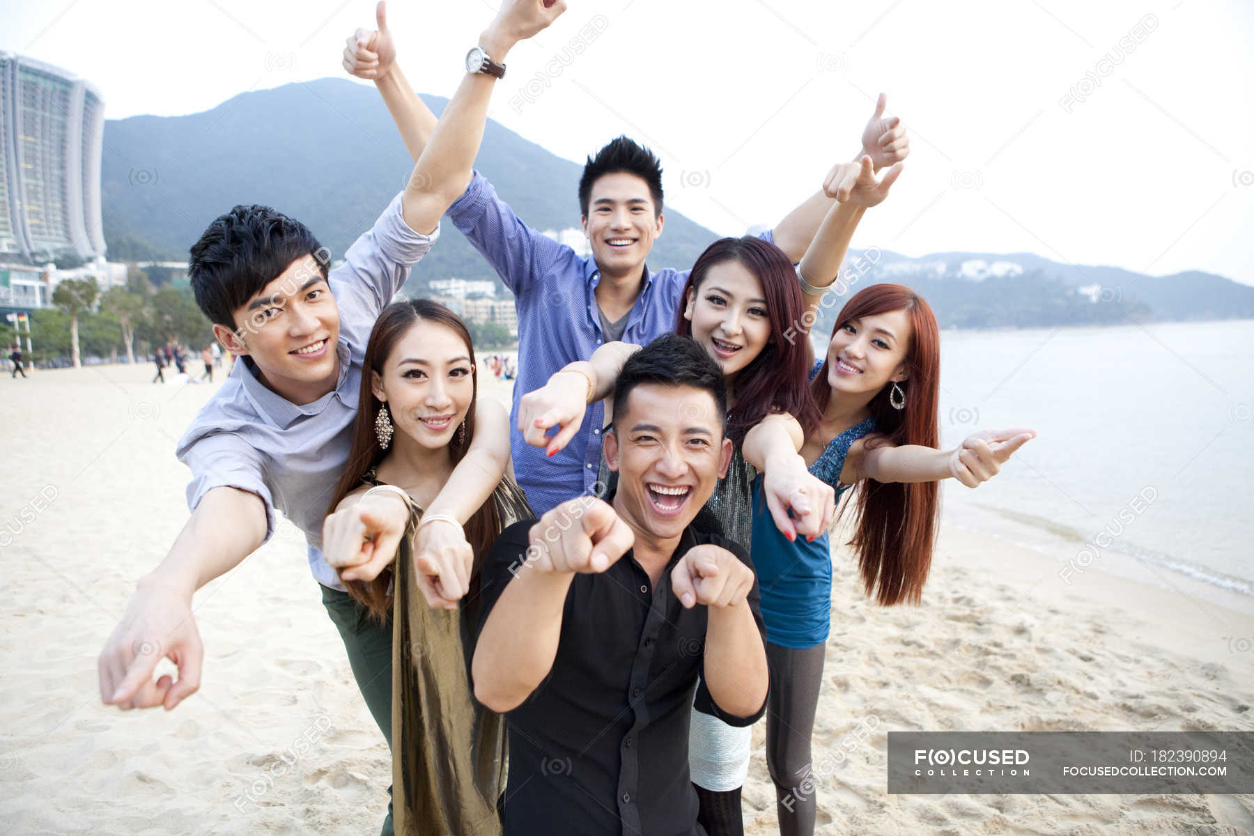 Chinese friends pointing and looking in camera on beach of Repulse Bay ...