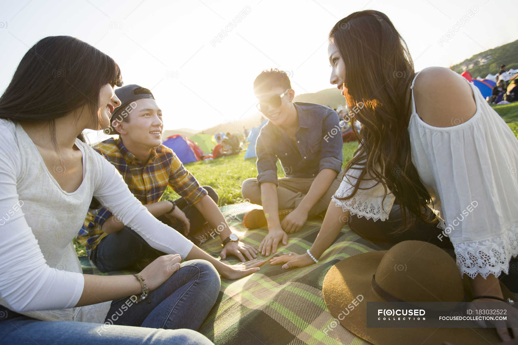 Chinese friends sitting on blanket at music festival — tents, Men ...