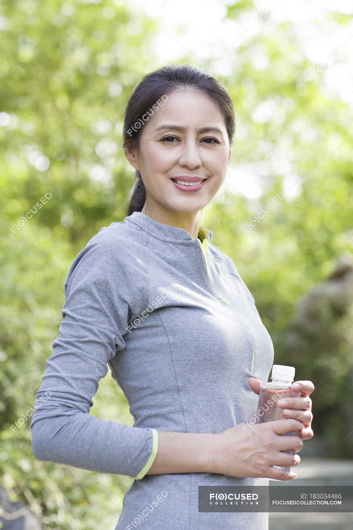 Mature Chinese Woman In Sportswear Holding Bottle With Water Female