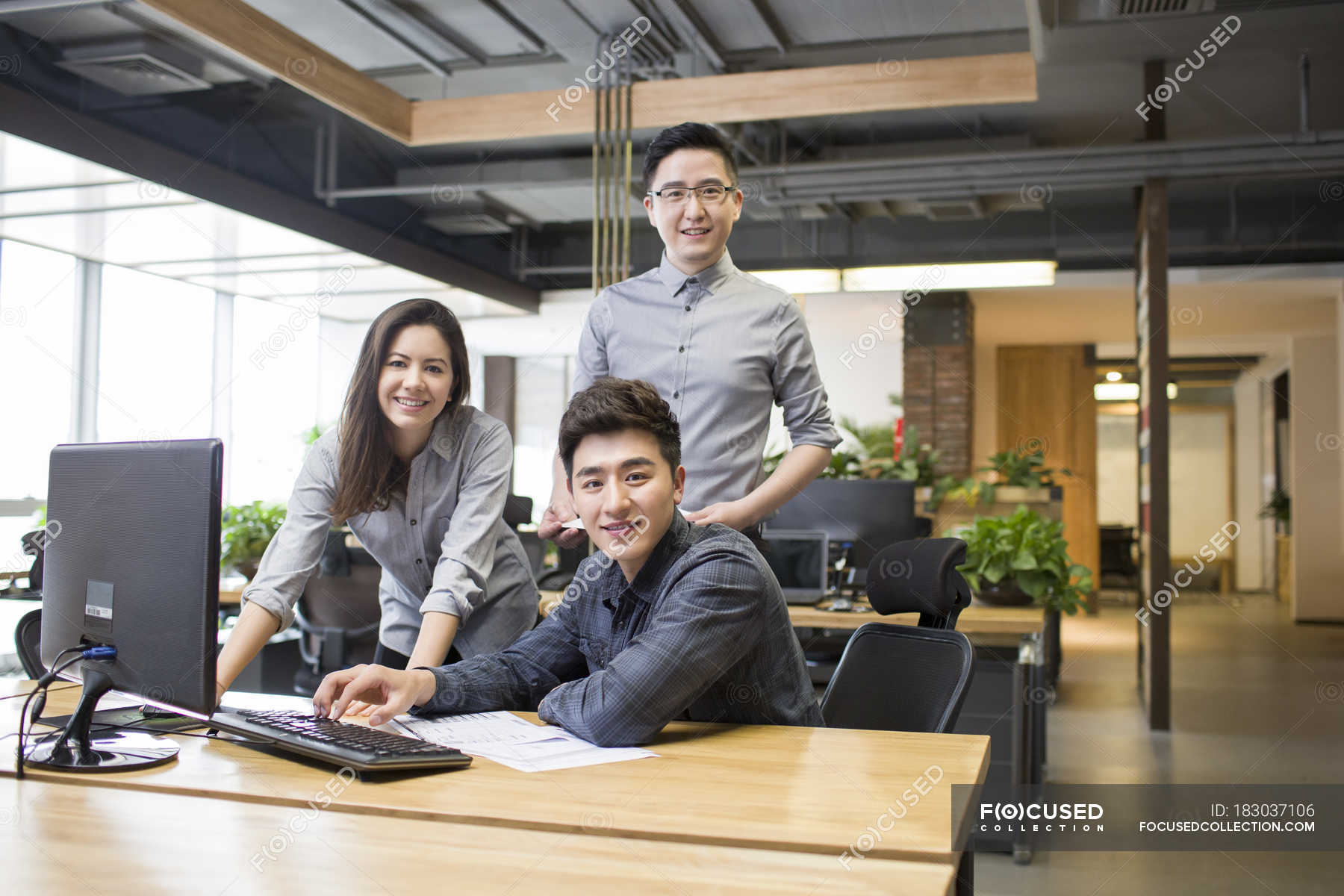 Chinese colleagues posing at desk in office — office workers