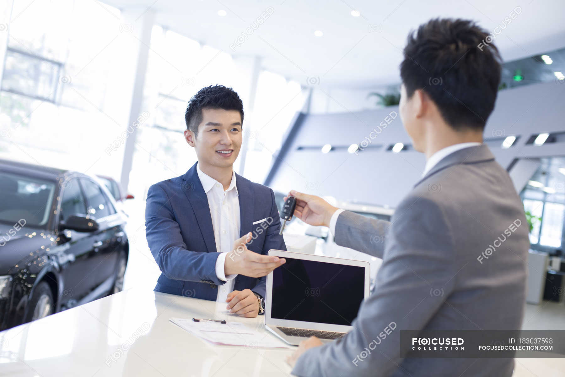 Chinese car dealer giving man car keys in showroom — shopping, Men ...