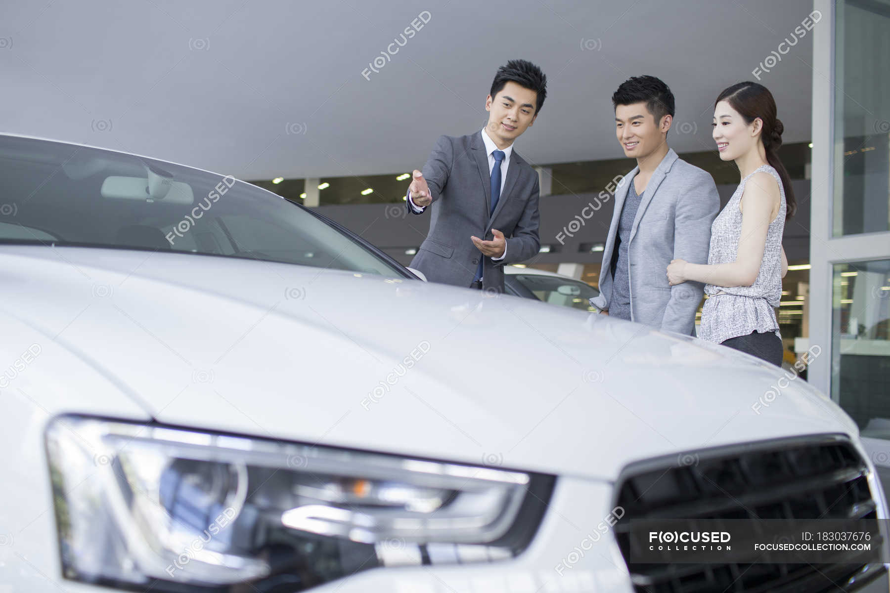 Chinese Couple Choosing Car With Dealer In Showroom — People, Auto ...