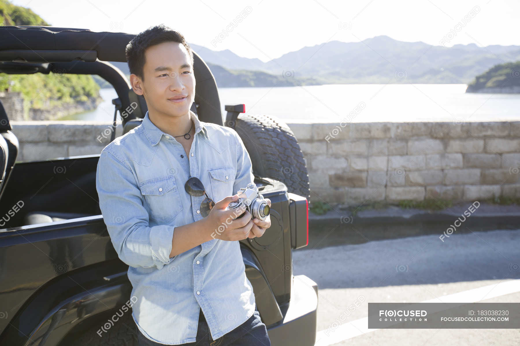 Chinese man standing with digital camera on lakeside — transportation ...