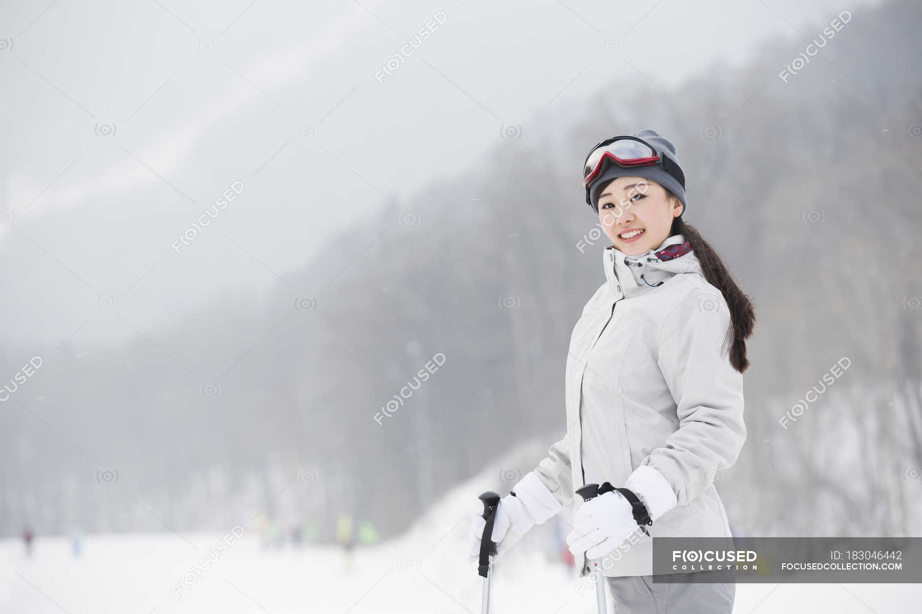 chinese-female-skier-standing-with-ski-poles-on-slope-winter-clothing