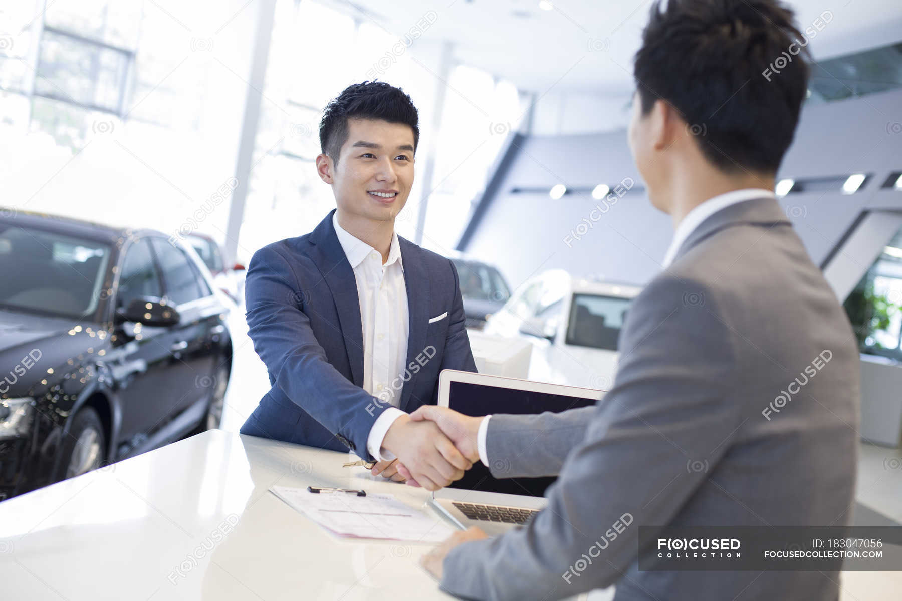 Chinese man shaking hands with car dealer in showroom — buying, Men ...