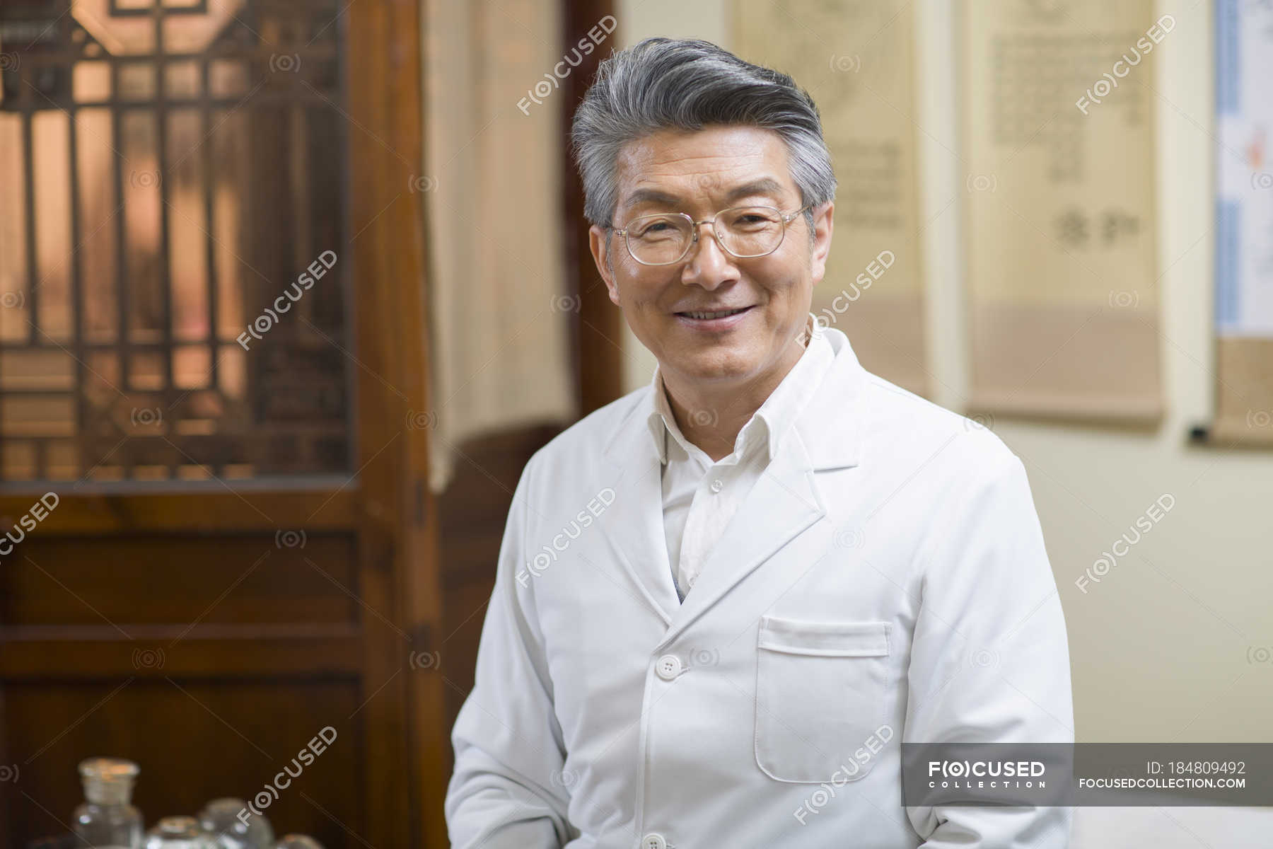 Senior chinese doctor standing in clinic and looking in camera ...