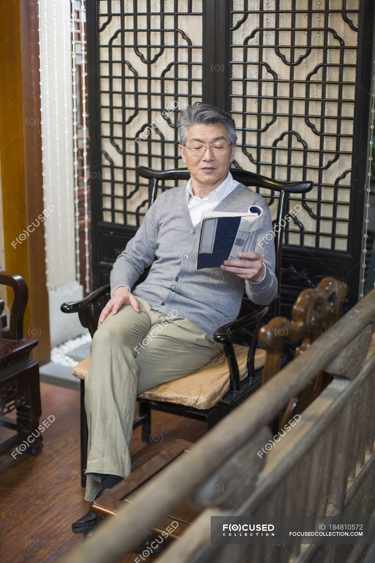 Senior Chinese man sitting in chair and reading journal — lifestyle ...