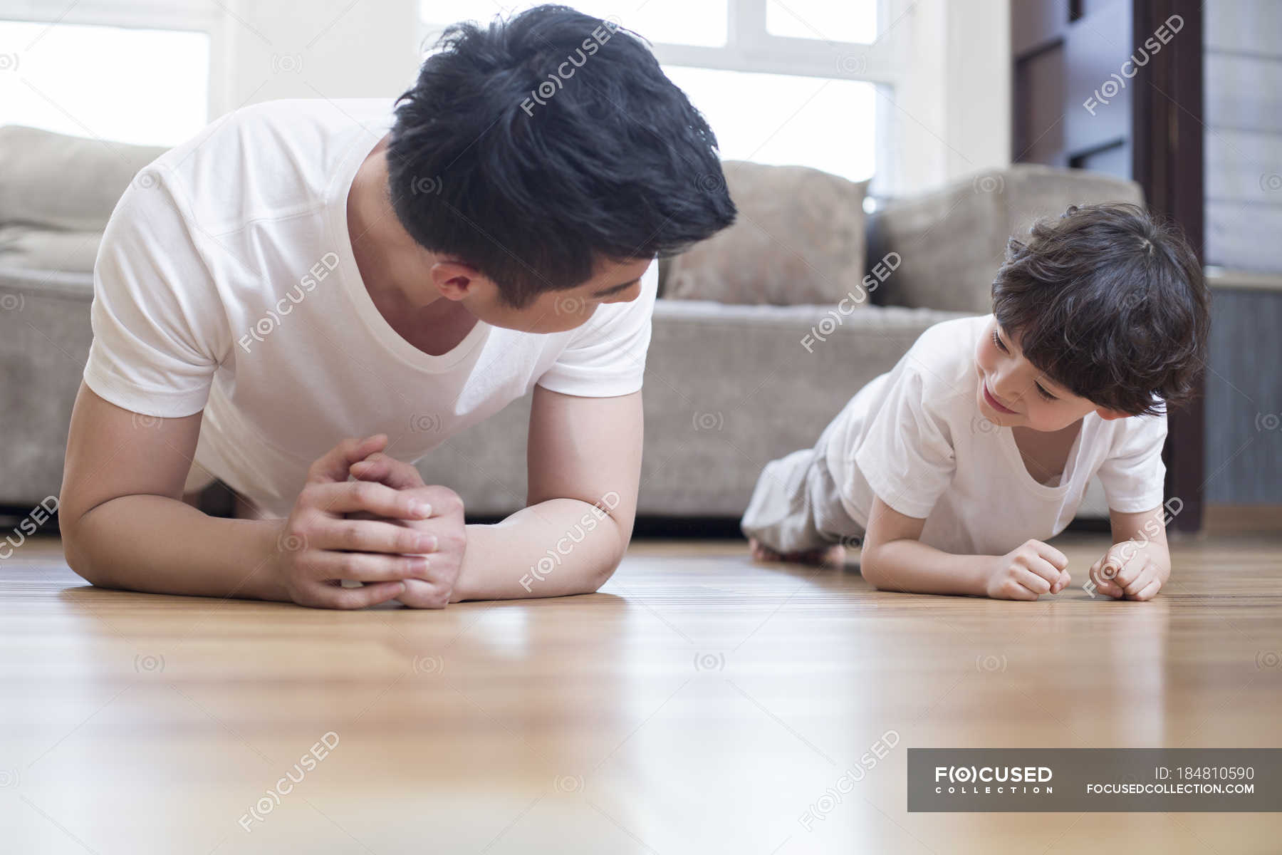 Chinese Father And Son Practicing Plank Pose At Home Healthy