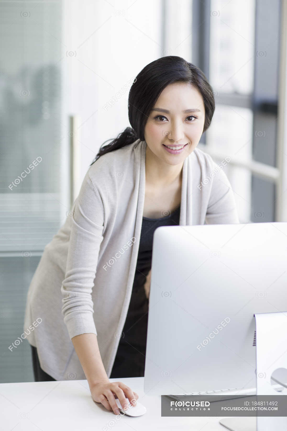 Chinese woman standing and using computer in office — corporate, Casual ...