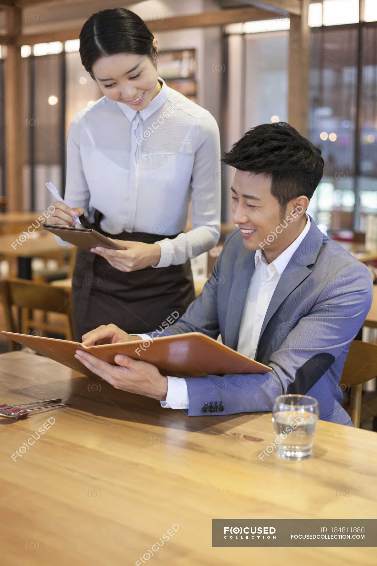 chinese-man-ordering-in-restaurant-with-waitress-differential-focus