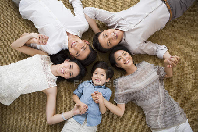 Chinese family three generations holding hands while lying on floor — Stock Photo