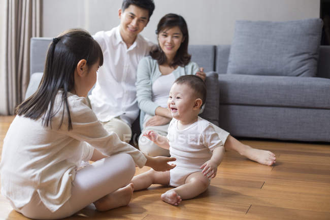 Chinese family sitting on wooden floor in living room — Stock Photo