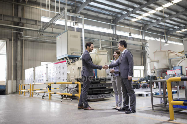 Бизнесмены пожимают руки на промышленном заводе — стоковое фото