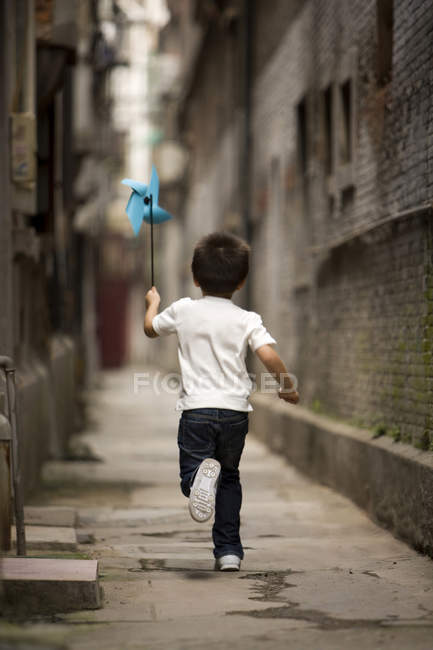Criança chinesa correndo com papel pinwheel — Fotografia de Stock