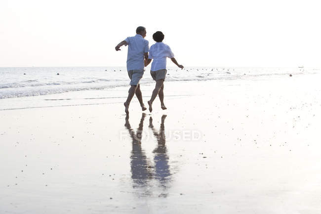 Senior chinesisches Paar läuft auf Sand am Strand — Stockfoto