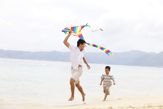 Отец и сын запускают воздушного змея на пляже — стоковое фото