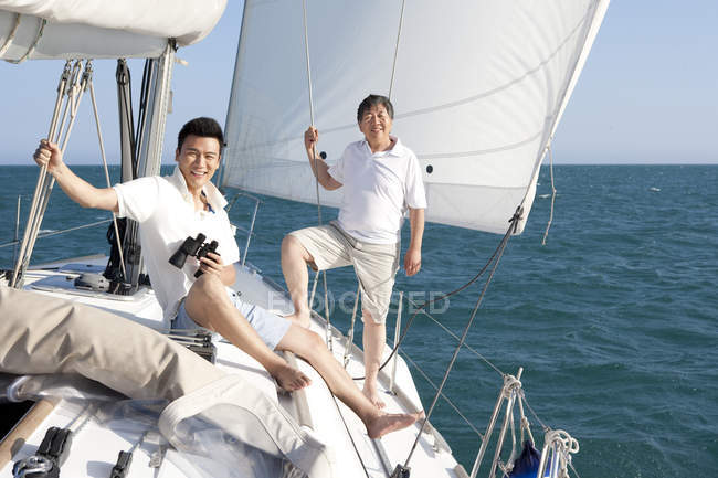 Chinesische junge und ältere Männer segeln auf Jacht — Stockfoto