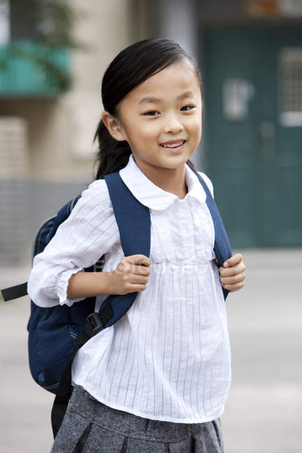 Chinese schoolgirl with backpack standing on street — Stock Photo