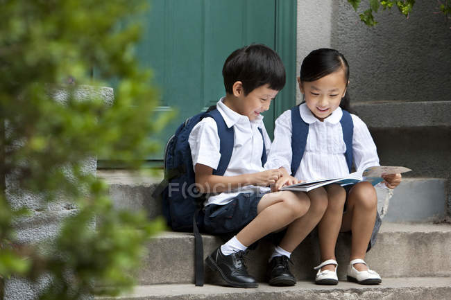 Chinese boy and girl studying on porch — Stock Photo