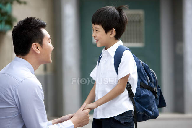 Père chinois et écolier tenant la main sur la rue — Photo de stock