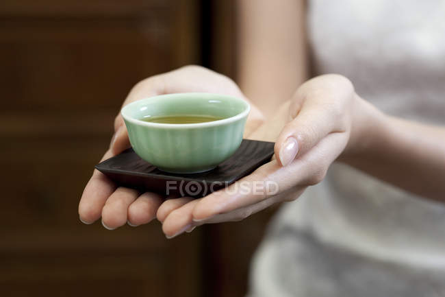 Close-up de mãos femininas segurando xícara de chá — Fotografia de Stock