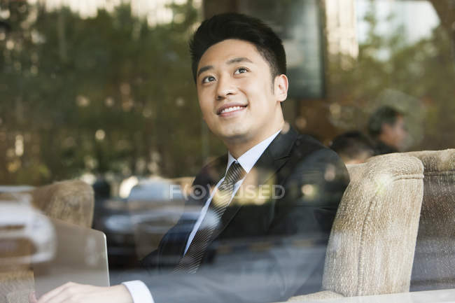 Homem de negócios chinês olhando através da janela no café — Fotografia de Stock