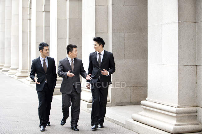 Des hommes d'affaires chinois marchent et parlent dans la rue — Photo de stock