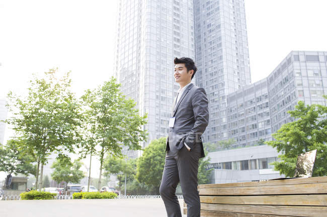 Hombre de negocios chino de pie en la calle y mirando a la vista - foto de stock