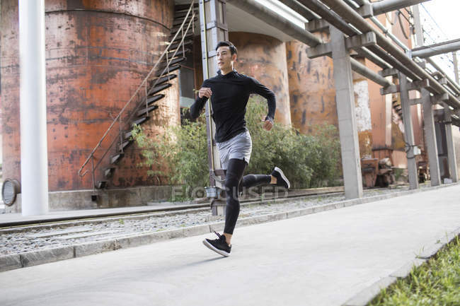 Chino atleta masculino trotando en la calle - foto de stock
