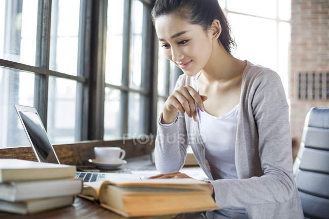Mujer china leyendo libro en la cafetería - foto de stock