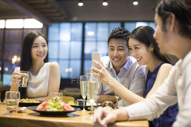 Asian friends taking selfie with smartphone while dinner in restaurant — Stock Photo