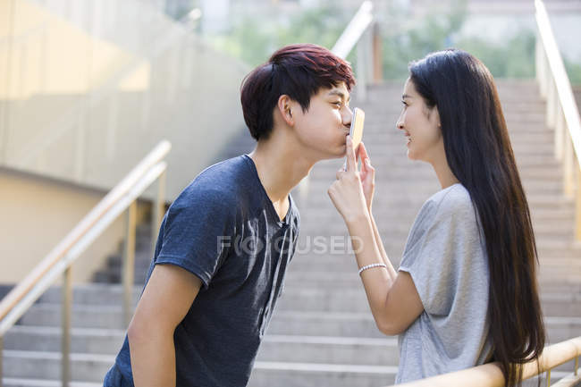 twin Pub Post Donna cinese mettendo smartphone per fidanzato bacio — scale, Ora legale -  Stock Photo | #178411506