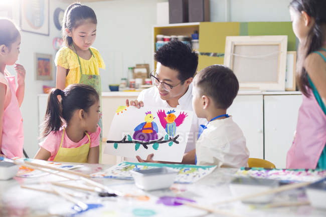 Китайські діти, дивлячись на картину в мистецтві клас з вчителем — стокове фото
