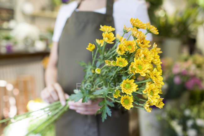 Female florist holding bunch of flowers — Stock Photo