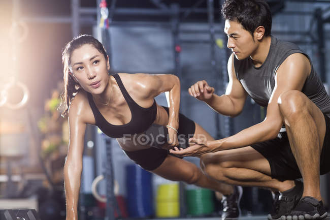 Mujer china trabajando con entrenador en gimnasio - foto de stock