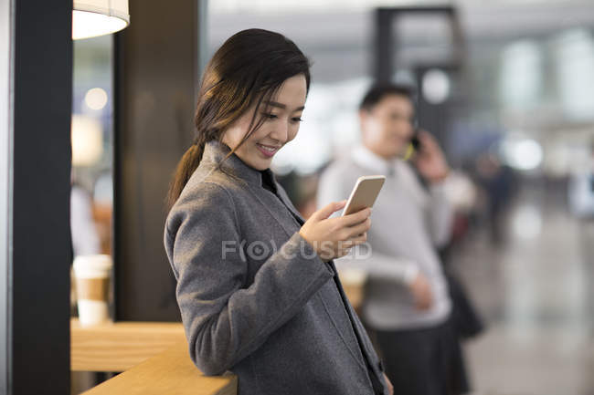 Азіатський жінка за допомогою смартфона в аеропорту — стокове фото