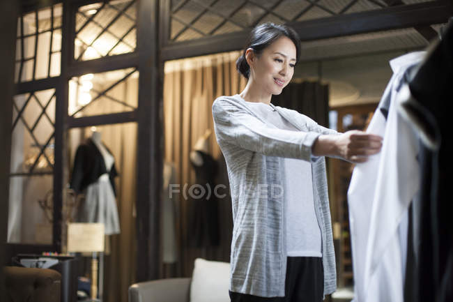 Китаянка смотрит одежду в магазине одежды — стоковое фото