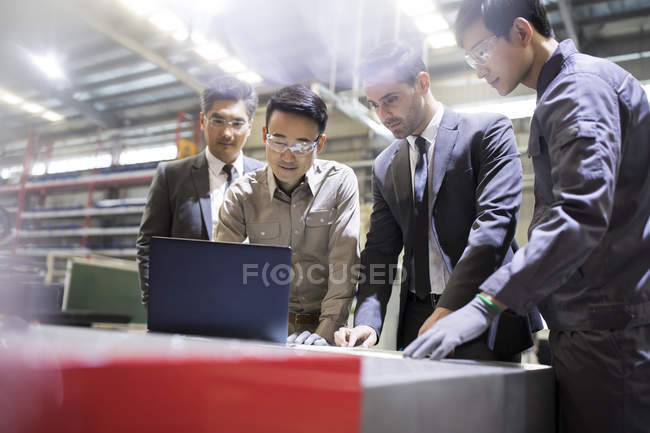 Uomini d'affari e ingegneri che utilizzano laptop in fabbrica industriale — Foto stock