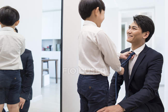 Menino chinês ajustando pai gravata — Fotografia de Stock