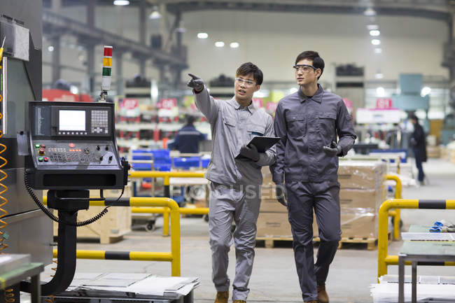 Confident Chinese engineers inspecting industrial factory with digital tablet — Stock Photo