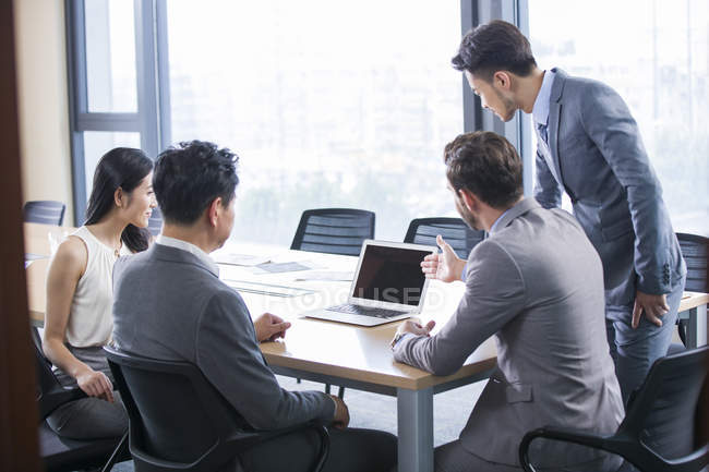 Geschäftsleute zeigen im Besprechungsraum auf Laptop — Stockfoto