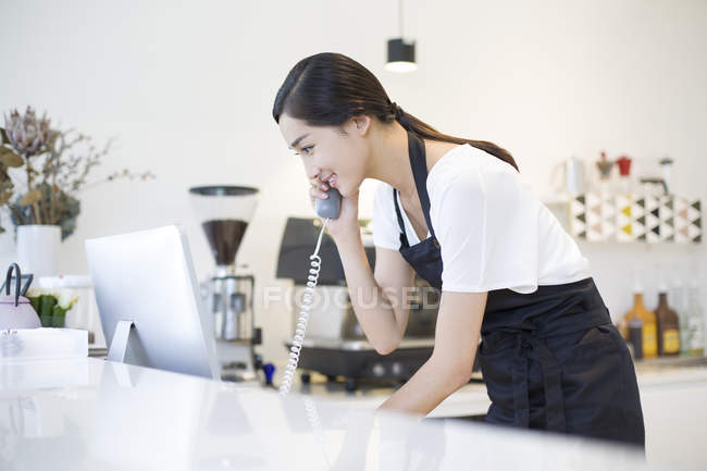 Chinese coffee shop owner talking on phone — Stock Photo