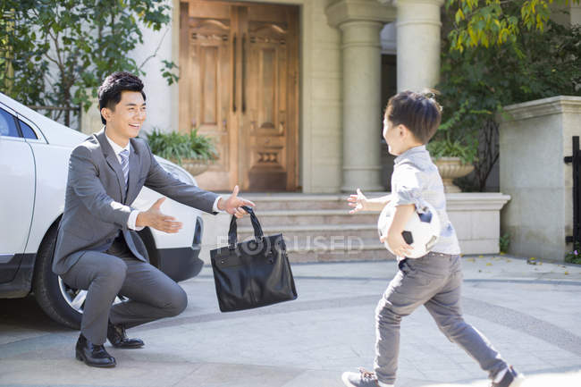 Chinese boy with football running towards to father — Stock Photo