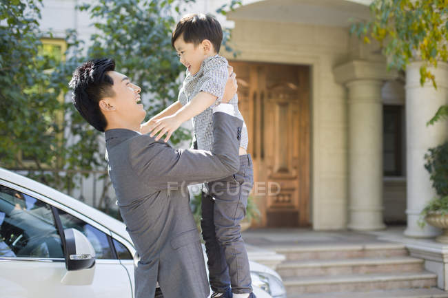 Chinese father carrying and lifting son on street — Stock Photo